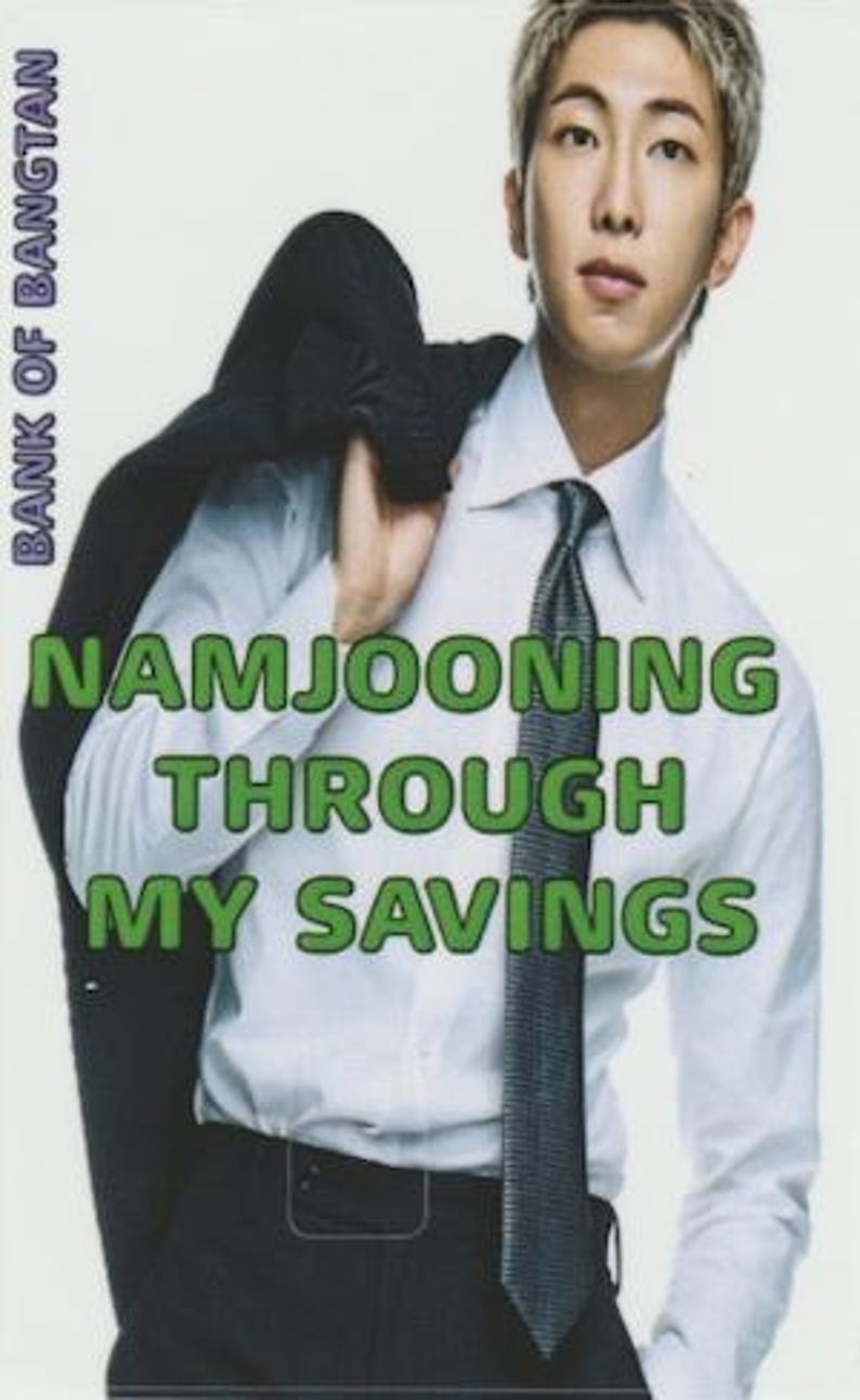 以下が含まれることがあります： 白いシャツと黒いネクタイを着た人物の画像で、肩に黒いスーツジャケットを着ています。画像には「BANK OF BANGTAN」と「NAMJOONING THROUGH MY SAVINGS」という文字が書かれています。