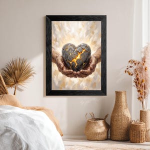 May include: A framed wall art print featuring a pair of weathered hands cupping a cracked, dark gray stone heart. The heart displays glowing golden light emanating from the fissures, set against a soft, ethereal, and light-colored background.