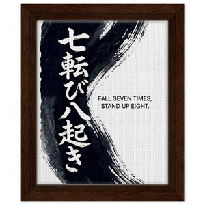 Peut inclure: Impression encadrée dans un cadre en bois marron foncé. L'œuvre présente une calligraphie japonaise et le texte anglais « FALL SEVEN TIMES, STAND UP EIGHT ». Le fond est blanc avec un motif de coup de pinceau bleu foncé.