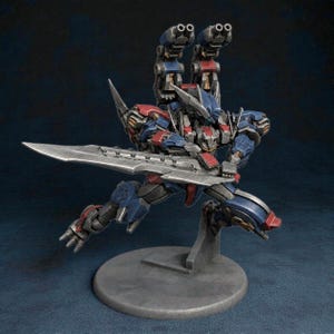 Puede incluir: Figura de acción detallada de un robot en una pose dinámica, empuñando una gran espada. La figura es predominantemente azul y roja con detalles plateados, y presenta dos torretas de armas en la espalda. Se apoya sobre una base gris.