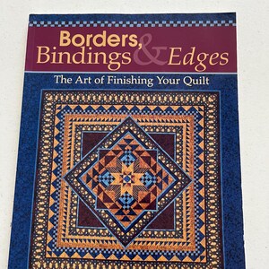 May include: A book titled "Borders, Bindings & Edges" with the subtitle "The Art of Finishing Your Quilt." The cover features a detailed quilt design in shades of blue, brown, and orange. The author's name, Sally Collins, is at the bottom.