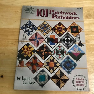 May include: A book titled "101 Patchwork Potholders" by Linda Causee. The cover features a grid of sixteen colorful, patterned potholders. The book includes full-size patterns. The American School of Needlework logo is visible.