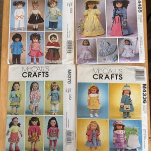 May include: Four McCall's Crafts sewing pattern envelopes labeled M6006, M4485, M6370, and M4336. Each envelope displays multiple photographs of dolls wearing various handmade outfits, including dresses, skirts, pants, jackets, and hats, with printed text and barcodes.