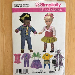 May include: A Simplicity 3873 sewing pattern envelope for 18" doll clothes. The front features illustrations of two dolls wearing various outfits, including a denim jacket, a skirt, and a hooded coat, along with smaller drawings of additional clothing options.