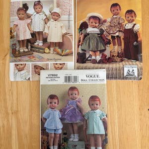 May include: Three Vogue Doll Collection sewing patterns labeled 7486, 7655, and V7892. Each paper envelope features color photographs of dolls wearing various outfits, including dresses, coats, and overalls, with printed text identifying the brand and pattern numbers.