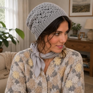 May include: A light gray crochet beanie with a delicate floral pattern and a ribbed brim, paired with a light gray neck scarf. The beanie features an intricate openwork design, while the scarf is tied in a simple knot around the neck.