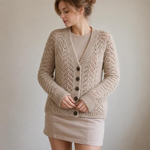 Könnte beinhalten: Eine beige Strickjacke mit V-Ausschnitt, strukturiertem Zickzack-Strickmuster und langen Ärmeln. Das Kleidungsstück verfügt über eine Knopfleiste mit fünf dunkelbraunen Knöpfen, gerippte Bündchen und einen gerippten Saum, getragen über einem beigen Oberteil und Rock.