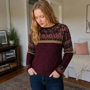 May include: A long-sleeved knit sweater featuring a deep burgundy solid-colored lower section with a cable knit texture, a horizontal tan band, and an upper yoke and sleeve section decorated with a multi-colored geometric fair isle pattern.