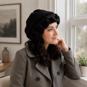 May include: A black knit beanie featuring a thick, braided cable-knit brim and a textured, solid-colored crown. The hat is constructed from yarn and sits snugly on the head, showcasing a detailed, chunky weave pattern throughout the entire design.