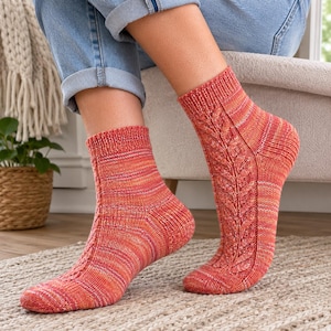 May include: A pair of ankle-length knit socks featuring a variegated color palette of orange, red, and yellow. The socks display a vertical cable knit pattern running along the outer side, finished with a ribbed cuff at the top of each sock.
