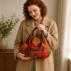 May include: A handbag featuring a multi-colored patchwork design with diamond-shaped segments in shades of orange, red, purple, and green. The bag has two dark brown leather handles attached with metal hardware and a small rectangular metal accent.