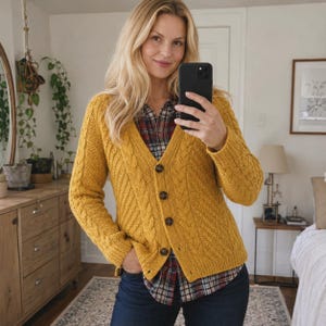 May include: A mustard yellow V-neck cardigan featuring a cable knit pattern on the front panels and sleeves. The garment has a button-down front with four dark brown buttons and ribbed cuffs and hem, worn over a plaid button-up shirt and dark jeans.