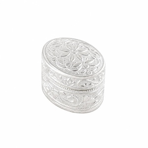 May include: A silver-colored, oval-shaped trinket box with intricate floral and leaf patterns. The box has a hinged lid and detailed embossed designs. The box is approximately 3 inches long and 2 inches wide.