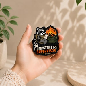 May include: A black rubber patch featuring a cartoon raccoon wearing sunglasses and a tactical vest, sitting in a chair next to a burning green dumpster. The raccoon holds a clipboard. The text reads DUMPSTER FIRE SUPERVISOR in white and orange.