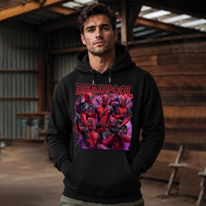 May include: Black hooded sweatshirt featuring a graphic of Deadpool characters in red and black. The word "DEADPOOL" is printed in red across the top. The sweatshirt has a front pocket and a drawstring hood.
