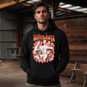 May include: Black hooded sweatshirt featuring the text "MIURA KOTA" in a retro style, with a graphic of a group of shirtless men. The sweatshirt has a drawstring hood and a front pocket.