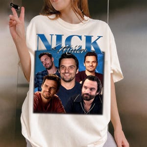 May include: Cream-colored t-shirt featuring a graphic of the name "Nick Miller" in blue, with a collage of images of a man. The design has a vintage aesthetic.