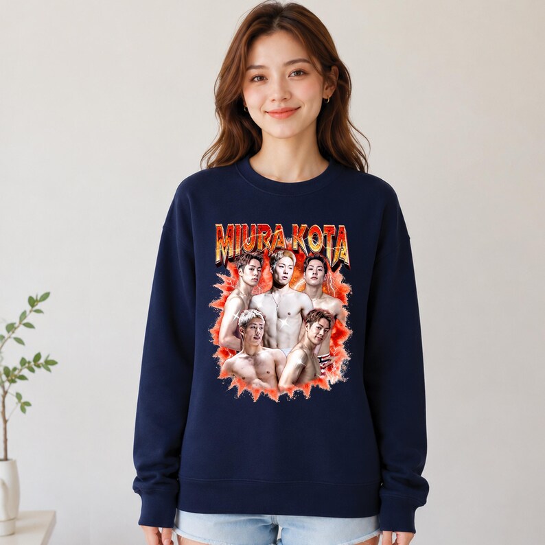 May include: Navy blue sweatshirt featuring a graphic of a group of men with the text "MIURA KOTA" in a retro style. The graphic is in shades of red, orange, and yellow. The sweatshirt is a crew neck style.