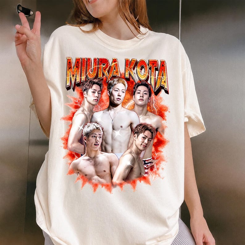 May include: Cream-colored t-shirt featuring the text "MIURA KOTA" in a gold and red design. The shirt displays a graphic of five shirtless men with a red lightning bolt background.
