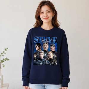 Op de afbeelding: Marineblauw sweatshirt met een grafische print van Steve Rogers uit de Captain America-serie. Het ontwerp bevat meerdere afbeeldingen van het personage en de tekst "STEVE Rogers" in blauw. Het sweatshirt heeft een ronde hals.