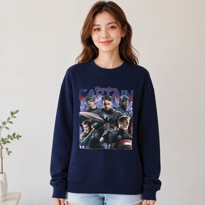May include: Navy blue sweatshirt featuring a graphic of Captain America with the text "America CAPTAIN". The graphic includes multiple images of Captain America in different poses. The sweatshirt is a crew neck style.