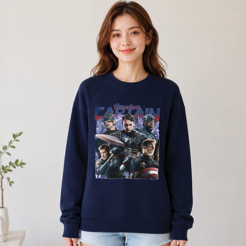 May include: Navy blue sweatshirt featuring a graphic of Captain America with the text "America CAPTAIN". The graphic includes multiple images of Captain America in different poses. The sweatshirt is a crew neck style.