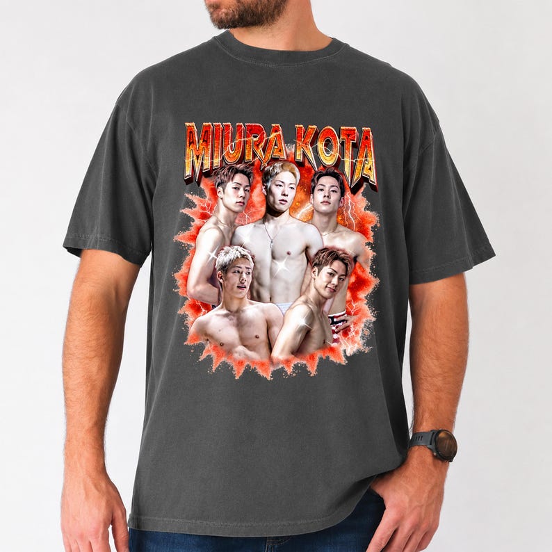 May include: Dark gray t-shirt featuring a graphic of five men with the text "MIURA KOTA" in a retro style. The graphic is set against a red and orange burst design. The shirt is a casual style.