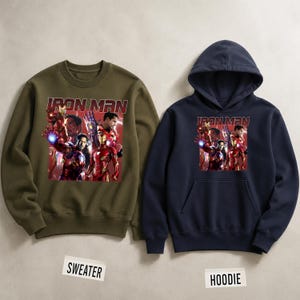 Puede incluir: Un su&eacute;ter verde oliva y una sudadera con capucha azul marino. Ambas prendas presentan un gr&aacute;fico de Iron Man y otros personajes de Marvel. El texto "IRON MAN" est&aacute; impreso en rojo sobre el gr&aacute;fico.