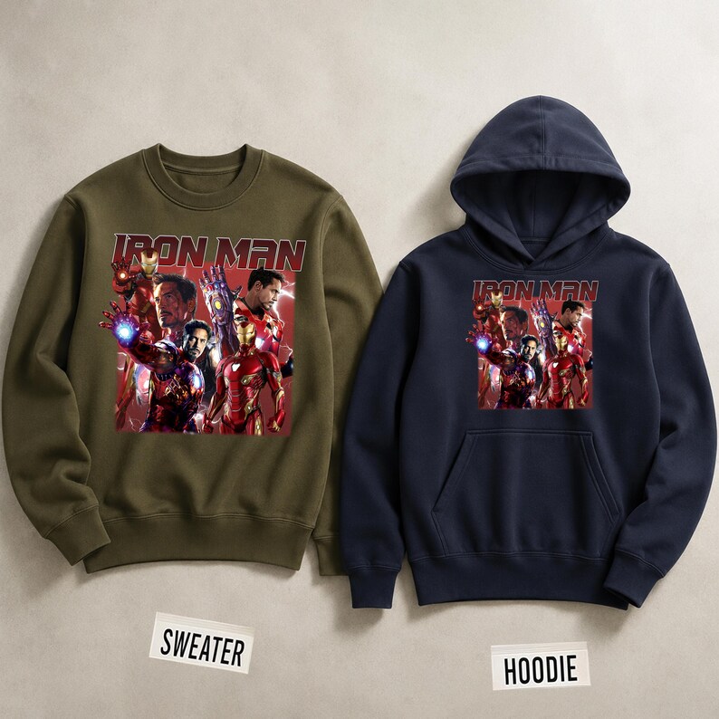 Puede incluir: Un su&eacute;ter verde oliva y una sudadera con capucha azul marino. Ambas prendas presentan un gr&aacute;fico de Iron Man y otros personajes de Marvel. El texto "IRON MAN" est&aacute; impreso en rojo sobre el gr&aacute;fico.