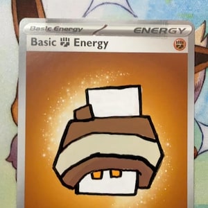 May include: A trading card featuring a hand-drawn illustration of a brown and white printer on an orange background. The card text reads Basic Energy at the top, with a small fist symbol. There is a handwritten date 09/32/01 and a signature at the bottom.