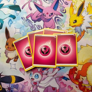 May include: Four pink Fairy-type energy trading cards from the Pok&eacute;mon card game. Each card features a central pink circular symbol with a black stylised star design surrounded by a white flame graphic, with the word ENERGY printed at the top.
