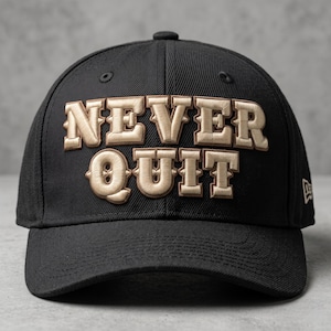 May include: A black baseball cap featuring the text NEVER QUIT embroidered in raised, metallic gold-toned lettering across the front panels. The cap has a structured crown, a curved brim, and a small brand logo on the side panel.