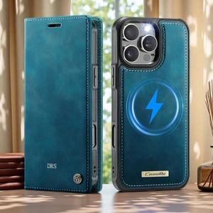 Peut inclure: Un étui de téléphone bleu sarcelle de type portefeuille avec une finition texturée. Le rabat avant porte les lettres DRS et un petit emblème métallique. L'arrière présente une découpe pour appareil photo et une icône de charge magnétique.