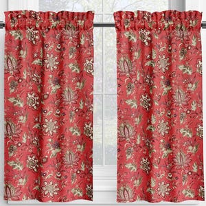 May include: Two red floral patterned window curtains hanging in front of a white window. The curtains have a repeating pattern of flowers and leaves in shades of green, brown, and beige.