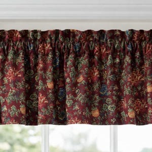 May include: A window valance featuring a deep burgundy background with a repeating botanical print of flowers and leaves in shades of green, gold, and blue. The fabric has a gathered rod pocket top, creating soft folds across the entire width.