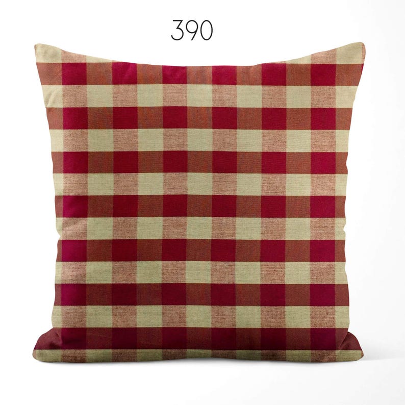 May include: A square throw pillow featuring a red and beige gingham check pattern. The number 390 is printed in black at the top center of the image. The pillow has a textured fabric appearance with a consistent grid design across the entire surface.