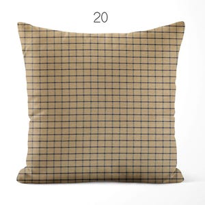 May include: A square throw pillow featuring a tan base color with a dark navy blue grid pattern. The number 20 is printed in black above the pillow. The design consists of thin horizontal and vertical lines forming a consistent check pattern.