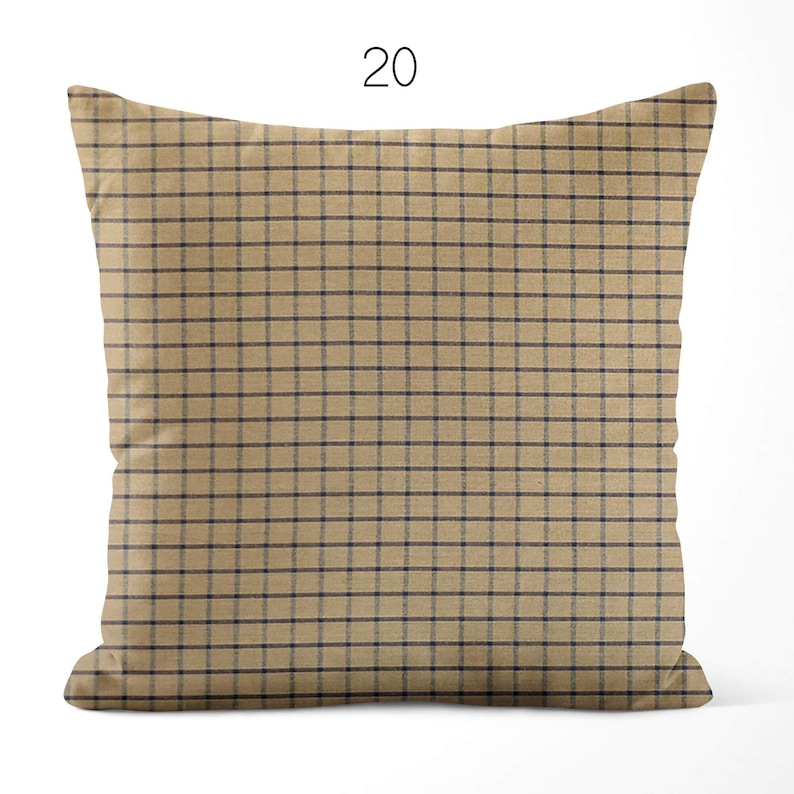 May include: A square throw pillow featuring a tan base color with a dark navy blue grid pattern. The number 20 is printed in black above the pillow. The design consists of thin horizontal and vertical lines forming a consistent check pattern.