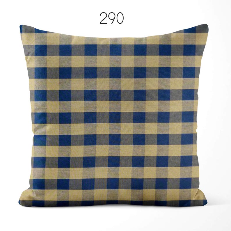 May include: A square throw pillow featuring a blue and beige checkered gingham pattern. The number 290 is printed in black at the top center of the pillow. The fabric has a visible woven texture throughout the entire surface of the cushion.