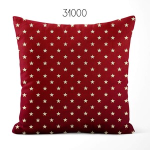 May include: A square throw pillow featuring a deep red background with a repeating pattern of small, off-white five-pointed stars. The number 31000 is printed in black at the top center of the image, positioned above the pillow.