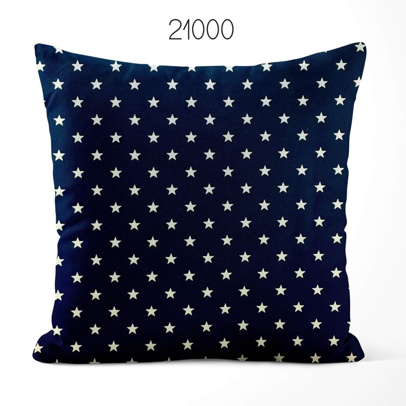 May include: A square throw pillow in a deep navy blue color featuring a repeating pattern of small, white, five-pointed stars across the entire surface. The number 21000 is printed in a simple black font centered above the top edge of the pillow.