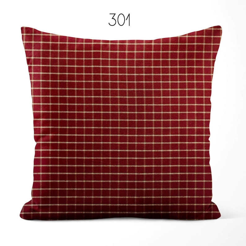 May include: A square throw pillow featuring a deep red fabric base with a thin, light beige grid pattern throughout. The number 301 is printed in black at the top center above the pillow. The pillow has a standard square shape with rounded corners.
