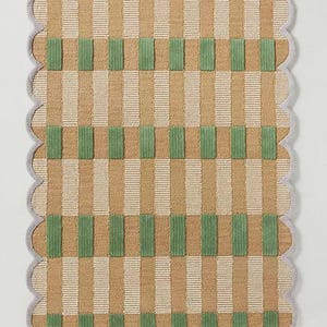 May include: A rectangular rug with a scalloped edge. The rug features a pattern of vertical stripes in tan and white, with green rectangular blocks. The border is a light grey colour.
