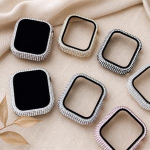 Pode incluir: Uma variedade de capas de relógio adornadas com joias em várias cores, incluindo prata, ouro e rosa. As capas são quadradas e incrustadas com pequenas pedras brilhantes. Os mostradores dos relógios são pretos.