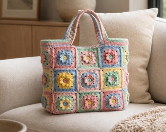 May include: A handmade crochet tote bag constructed from multiple square panels featuring raised floral centers in pastel shades of pink, yellow, blue, and green. The bag includes two matching crochet handles and a structured rectangular base.