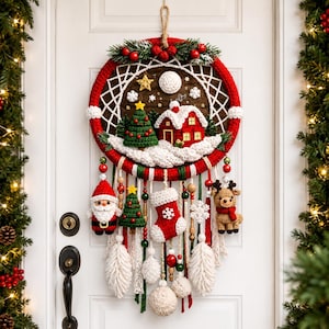 May include: A circular Christmas wall hanging featuring a crocheted winter scene with a red house, green tree, and white snow. The hoop is wrapped in red yarn and decorated with hanging crocheted ornaments including Santa, a stocking, and a reindeer.