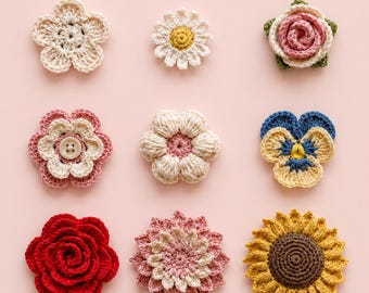 May include: Nine handmade crochet flowers in various designs and colors, including a daisy, rose, and sunflower. The flowers are in shades of white, pink, yellow, blue, and red, arranged on a light pink background. These decorative flowers are perfect for crafting projects.