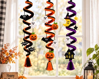 May include: Three hanging crochet spiral decorations featuring Halloween themes. Two spirals are black and orange, one is black and purple. They are adorned with crocheted ghosts, pumpkins, bats, spiders, a moon, a star, and a haunted house, ending in tassels.