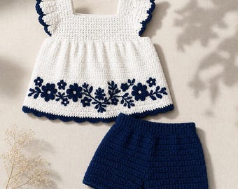 Könnte beinhalten: Ein weißes Häkeloberteil mit Flügelärmeln und einem dunkelblauen Blumenstickmuster am Saum, kombiniert mit einer einfarbigen dunkelblauen Häkelshorts. Das Oberteil hat einen eckigen Ausschnitt und dunkelblaue Bogenkanten am Saum.