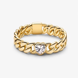 Può includere: Un anello a maglie color oro con una pietra preziosa trasparente a forma di cuore al centro. La fascia è composta da maglie metalliche intrecciate con una finitura liscia e lucida e un segmento rettangolare piatto opposto al cuore.